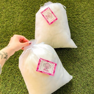 Duas almofadas brancas em saco transparente com etiquetas cor-de-rosa sobre relva artificial verde.