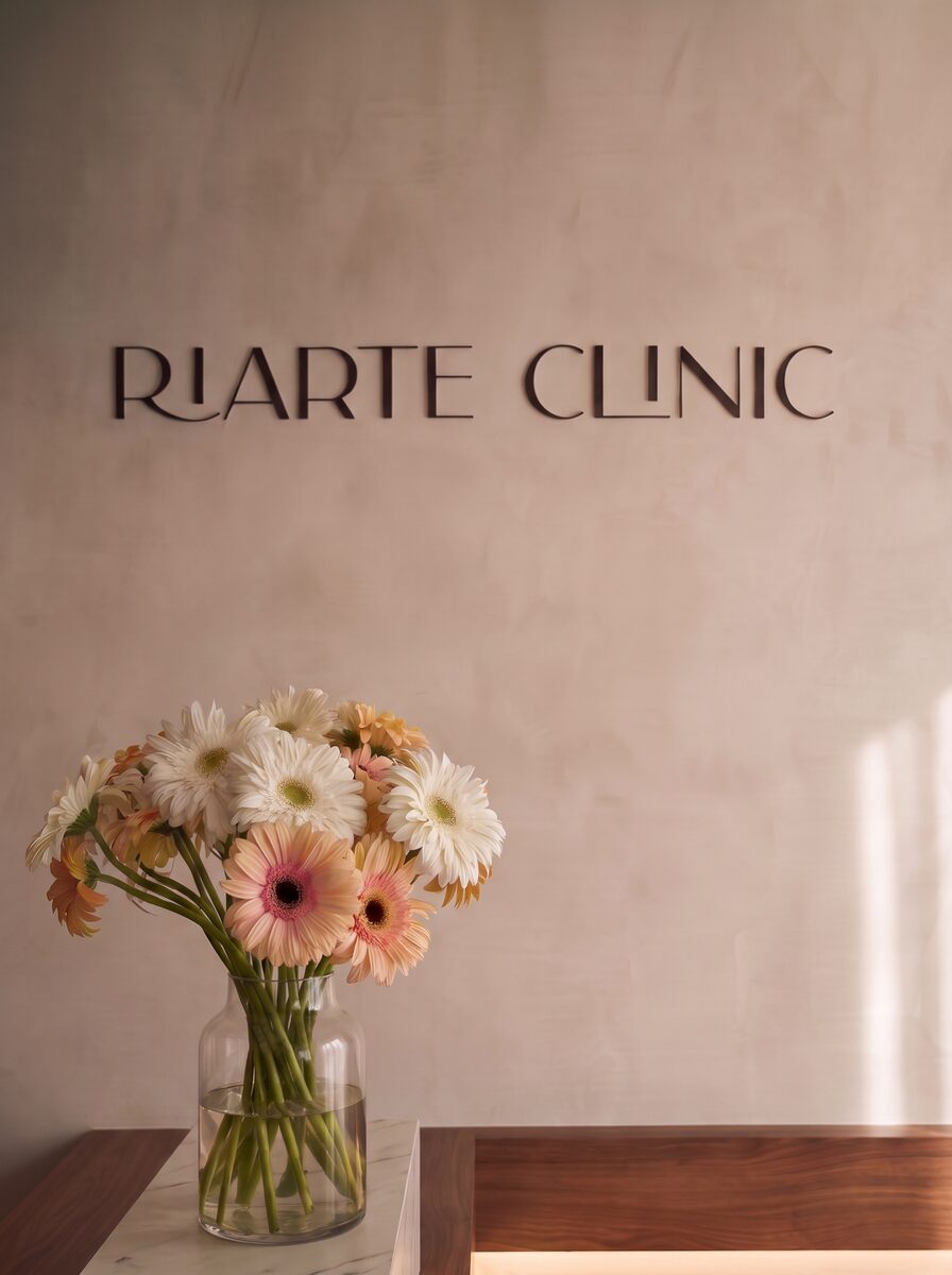 Parede da receção com o letreiro Riarte Clinic e um arranjo de gerberas