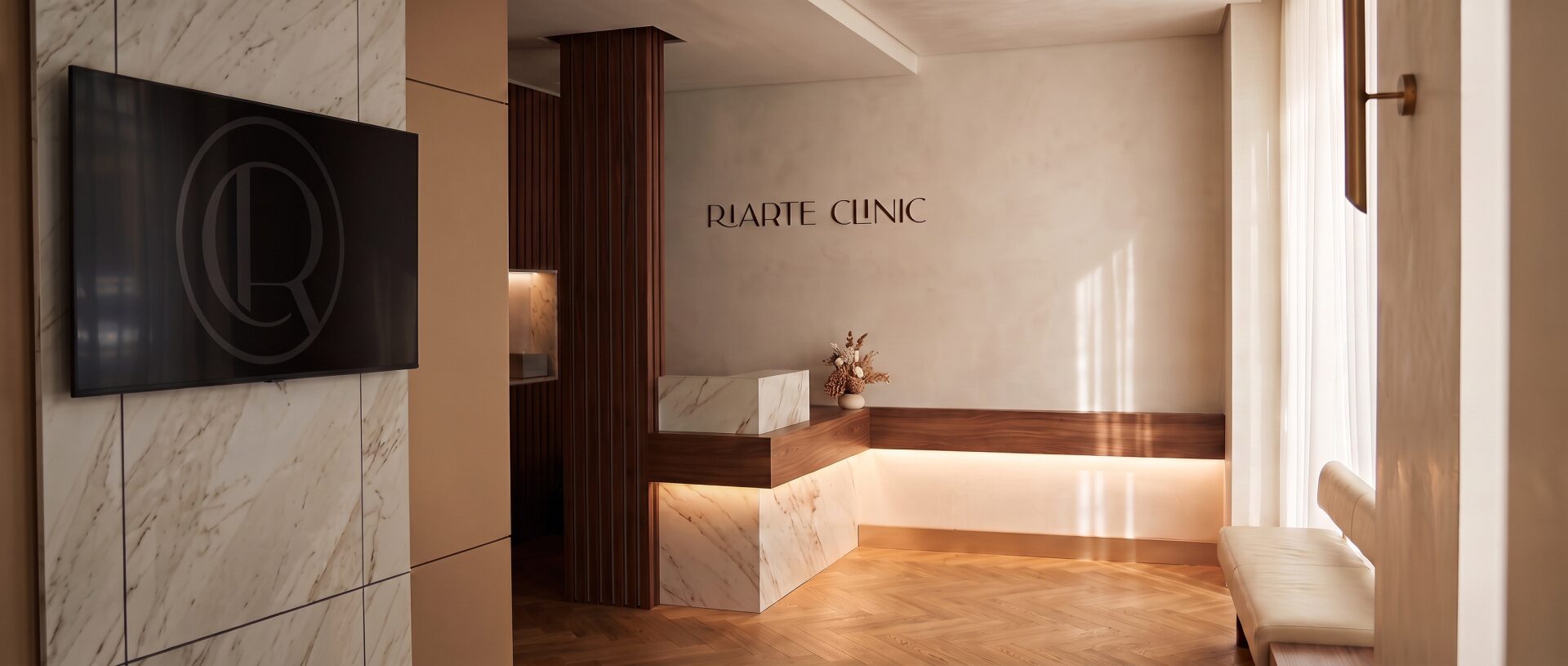 Rece&ccedil;&atilde;o da Riarte Clinic, com balc&atilde;o em m&aacute;rmore retroiluminado e parede em ripado de nogueira