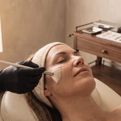 Mulher recebendo tratamento facial com pincel em ambiente de estética