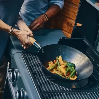 Frigideira wok preta com legumes coloridos numa grelha de gás preta