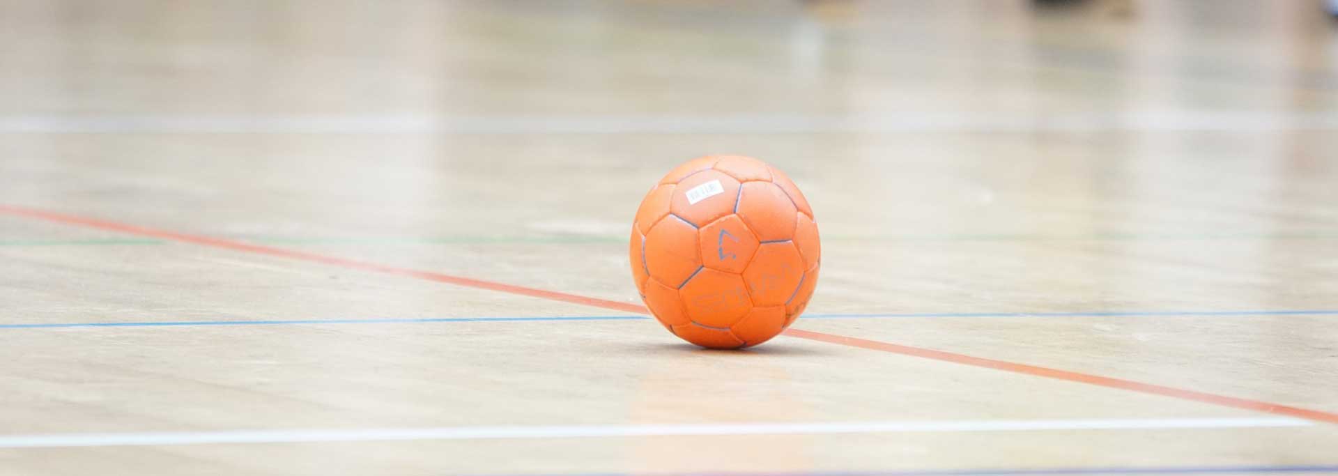 REMOZILL- Tira Resinas Bola de futsal laranja com padrão hexagonal sobre chão de quadra desportiva