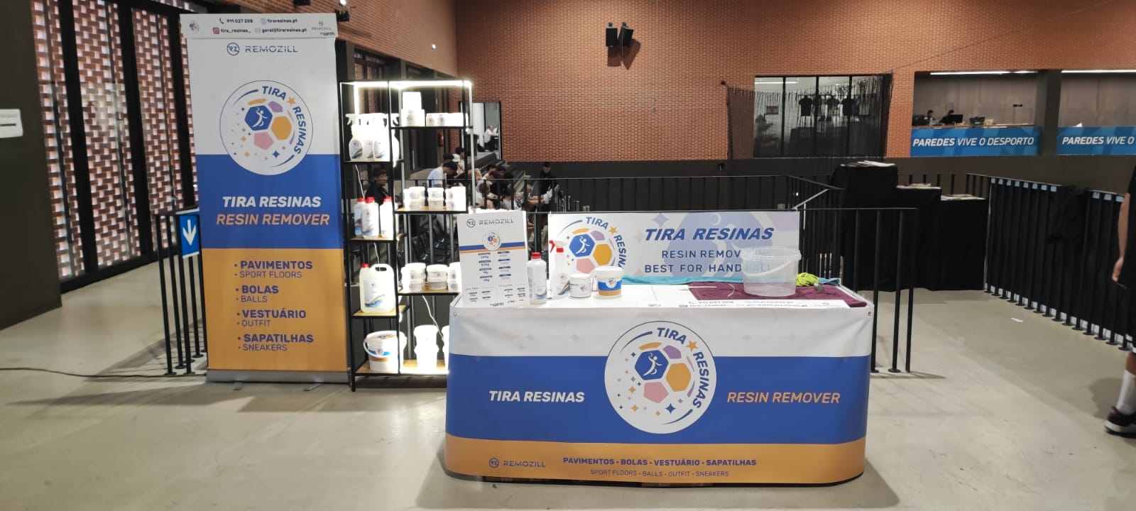 Stand de remoção de resinas com mesa azul e branca e banner em interior com paredes de tijolos