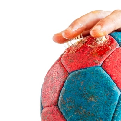 Bola de andebol azul e vermelha a ser limpa com escova