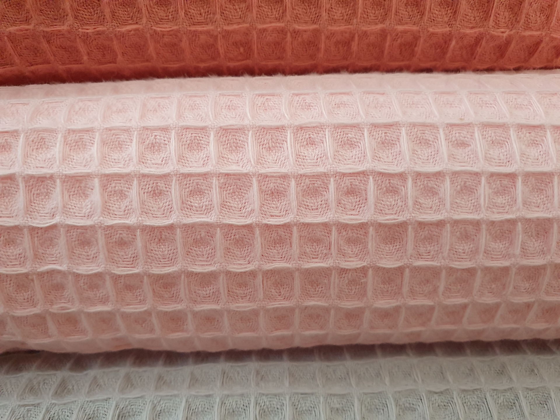 Tecido Waffle Rosa Bebé Três rolos de tecido em padrão xadrez com textura em waffle, nas cores laranja, rosa claro e cinza claro.
