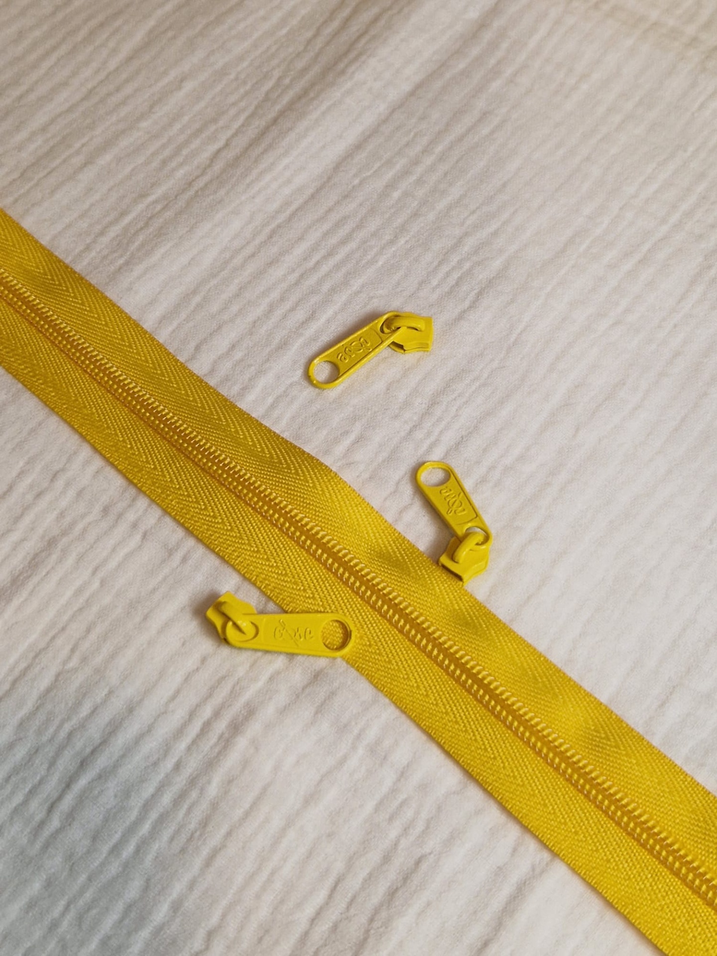 Fecho e cursor malha 5 Amarelo Gema Fecho éclair amarelo com cursoras, sobre tecido branco texturizado