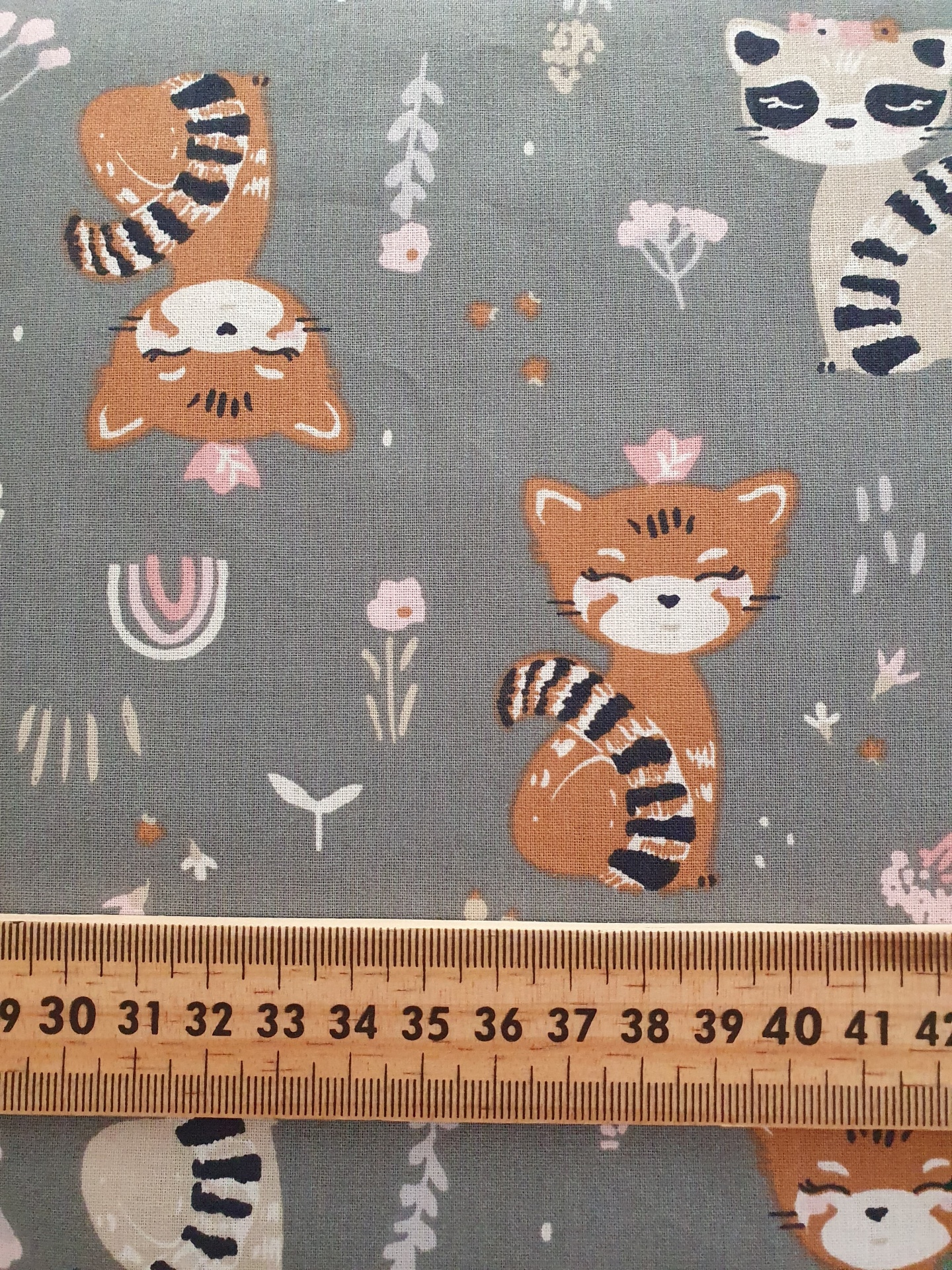 Sweet Forest tecido cinza com padrão de gatos laranja e branco, flores e folhas em tons pastéis, com régua de madeira