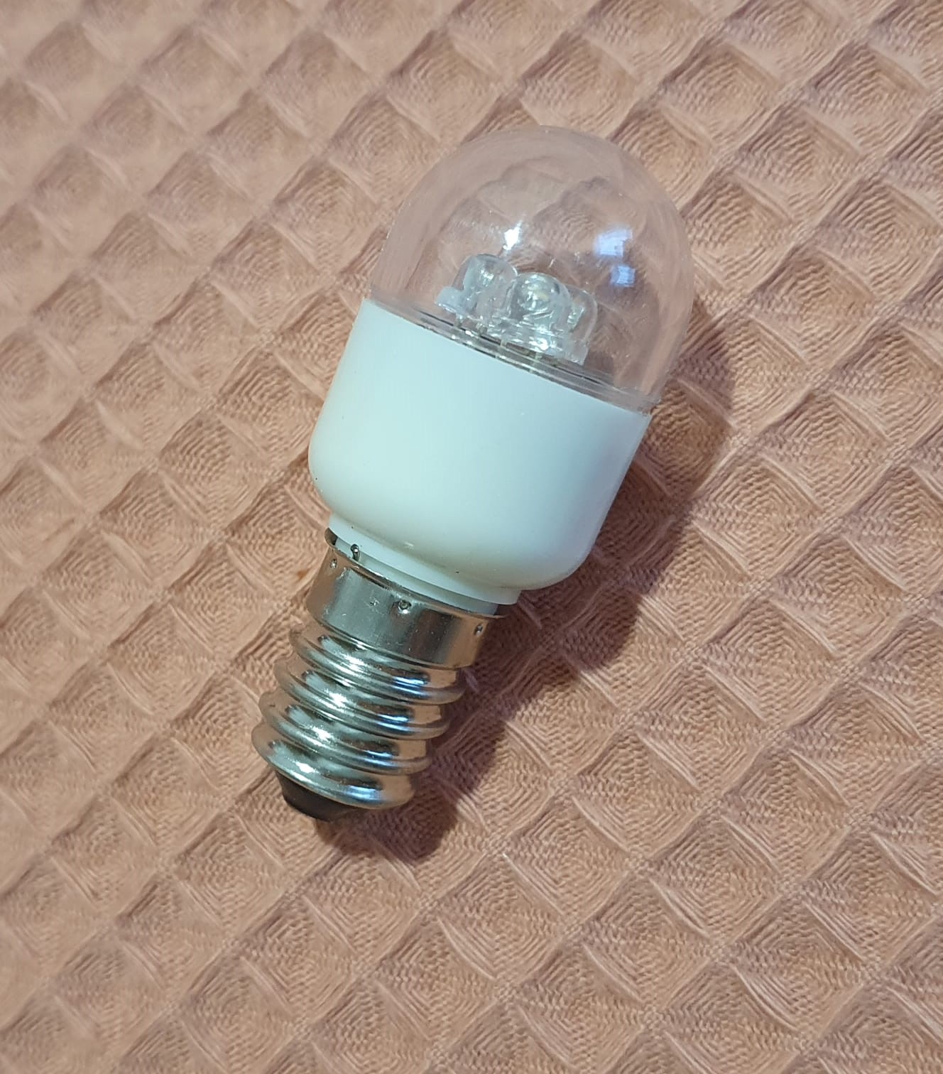 Lâmpada de Rosca Lâmpada LED pequena com base metálica e vidro transparente sobre tecido bege texturizado