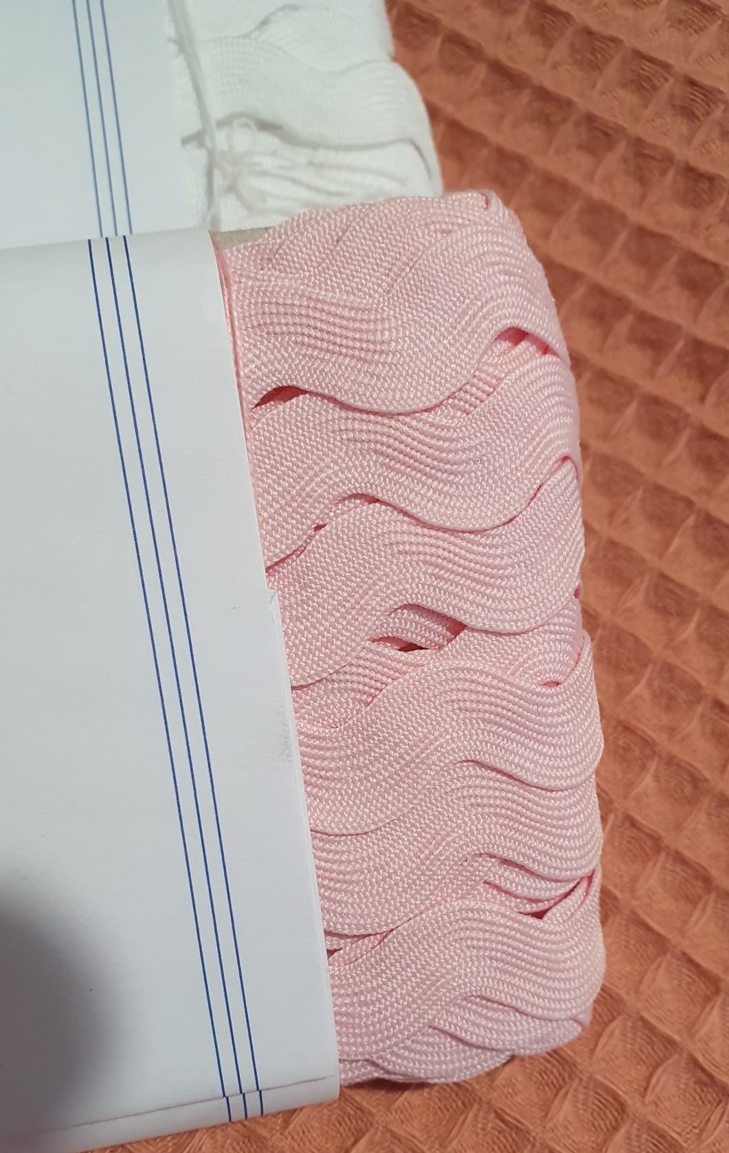Fita grega ou espiguilha Rosa bebé Pack de elásticos ondulados cor-de-rosa e branco sobre tecido acolchoado cor de ferrugem