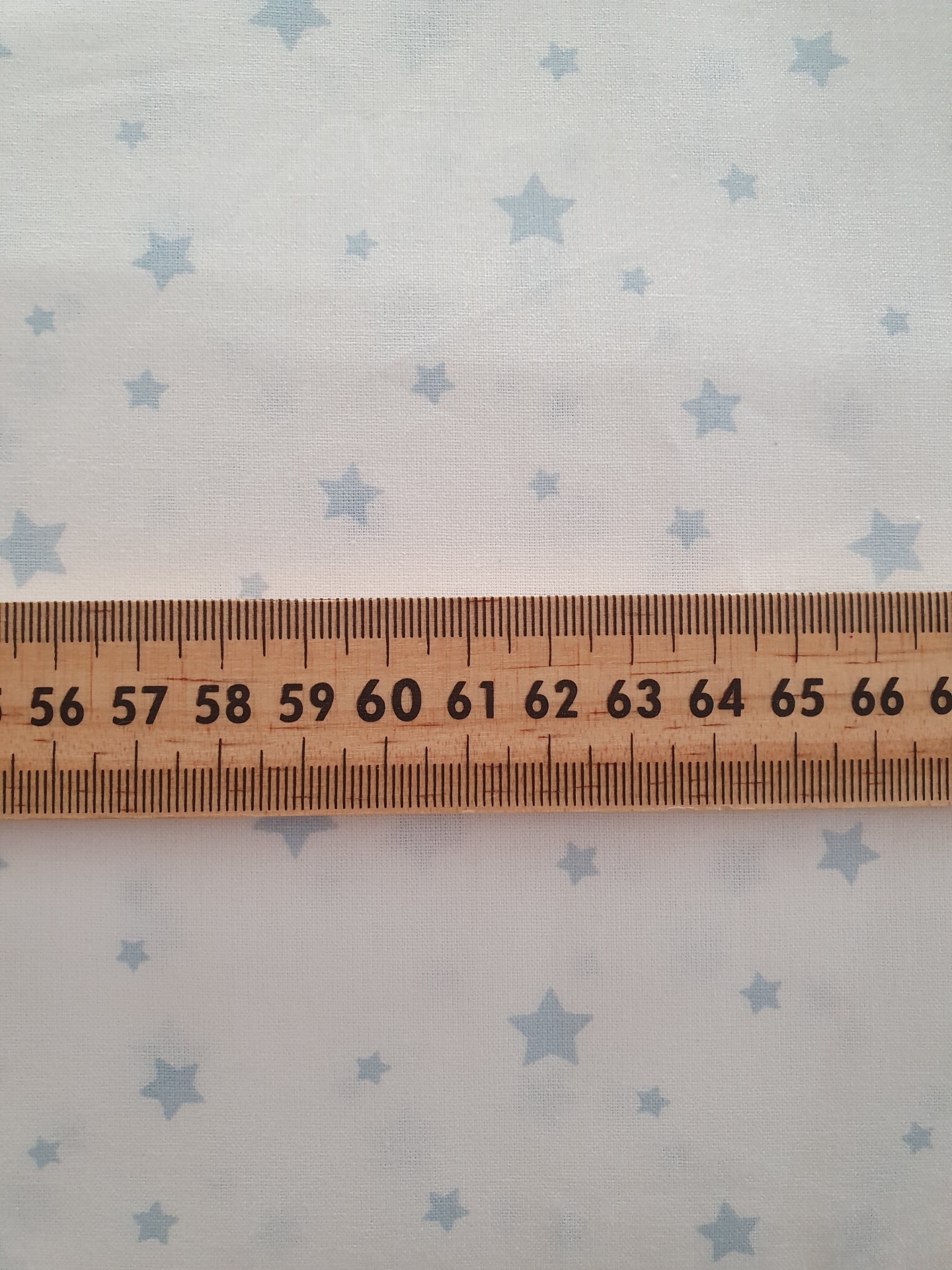 Estrelado Azul fundo branco tecido branco com estrelas azuis claras e régua de madeira sobre ele