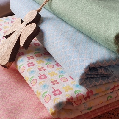 Tecidos coloridos dobrados com diferentes padrões e enfeite de anjo em madeira