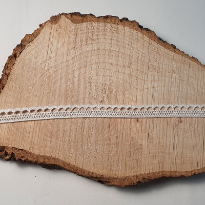 Fita de renda branca sobre fatia de corteza de madeira