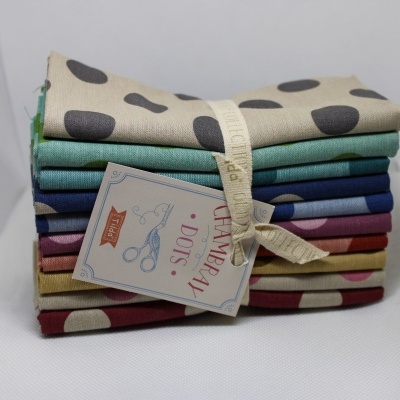 Conjunto de tecidos coloridos com padrão de manchas redondas amarrados com fita e etiqueta