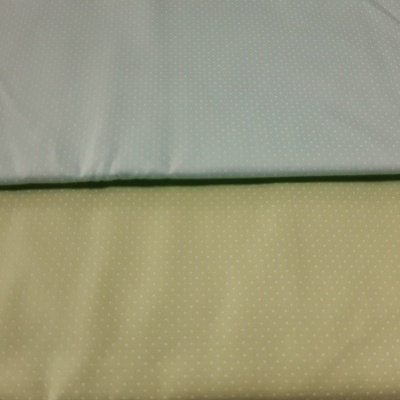 Dois tecidos de cores azul claro e bege claro com padrão de pequenos pontos