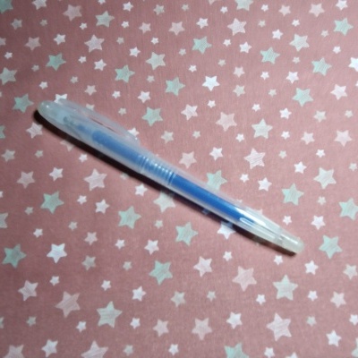 Caneta esferográfica azul sobre tecido rosa com estrelas brancas e cinza
