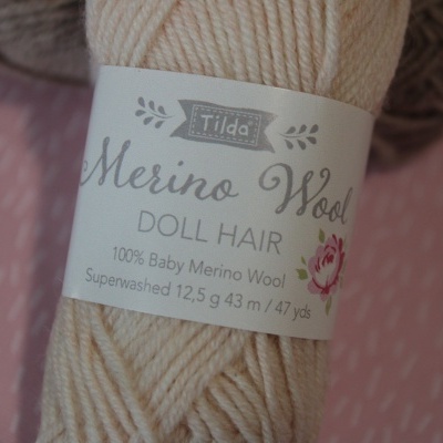 Novelo de lã Merino Wool bege da Tilda com etiqueta informativa sobre composição e medidas.