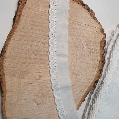 Fita branca bordada sobre madeira cortada