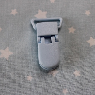 Prendedor cinzento claro sobre tecido cinza com estrelas brancas