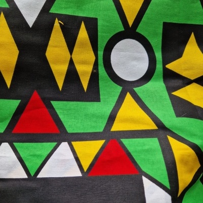 Pano com padrão geométrico colorido em verde, amarelo, vermelho, branco e preto