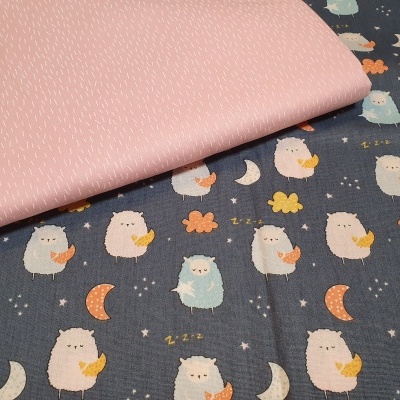 Tecidos com padrões, um rosa claro com linhas brancas e outro azul escuro com corujas e luas coloridas.