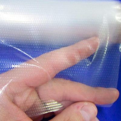 Plástico transparente texturizado com pontos, segurado por uma mão sobre fundo azul