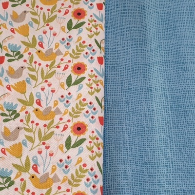 Dois tecidos lado a lado, um com padrão colorido de pássaros e flores e outro azul claro texturizado.