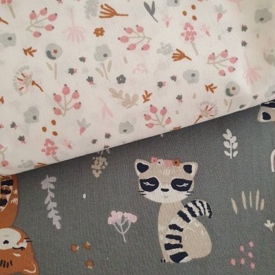 Dois tecidos, um branco com flores pequenas coloridas e outro cinza com desenhos de animais e flores