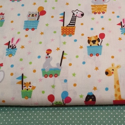 Tecido branco com padrão de animais em carrinhos coloridos e tecido verde claro com bolinhas brancas