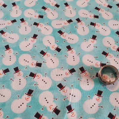 Tecido estampado com bonecos de neve brancos sobre fundo azul e uma argola metálica