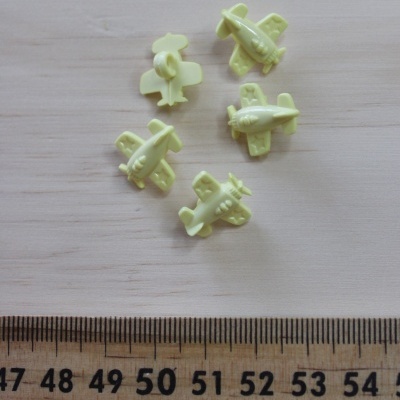 Cinco miniaturas amarelas de aviões ao lado de uma régua de madeira.