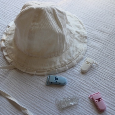 Chapéu branco de tecido com quatro presilhas coloridas em fundo branco