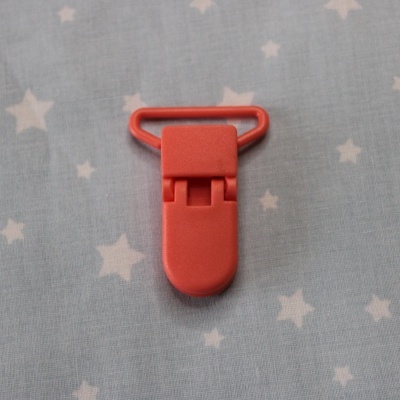 Clipe vermelho sobre tecido cinzento com estrelas brancas