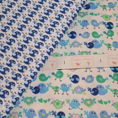 Tecido com padrões de pássaros coloridos e flores e uma fita decorativa com texto e imagens.