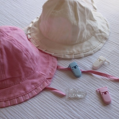 Dois chapéus de tecido rosa e branco e quatro presilhas de plástico