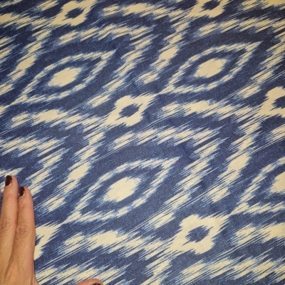 Tecido azul e branco com padrão geométrico e mão com unhas castanhas