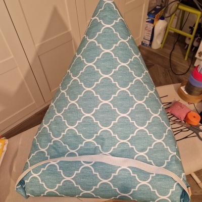 Almofada triangular azul com padrão branco e faixa branca na base