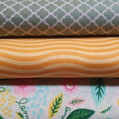 Três tecidos dobrados com padrões geométricos, riscas e flores coloridas
