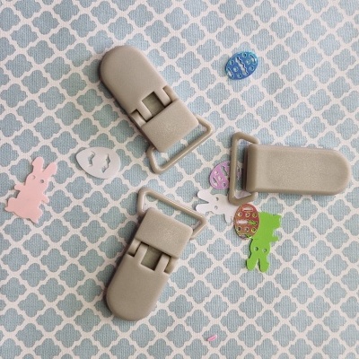 Três presilhas bege em pano com padrão branco e azul, junto a figuras coloridas de coelhos e ovos.