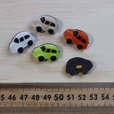 Cinco botões de carros coloridos sobre madeira com régua