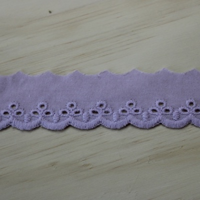 Tira de tecido lilás bordada com padrão floral e orla ondulada