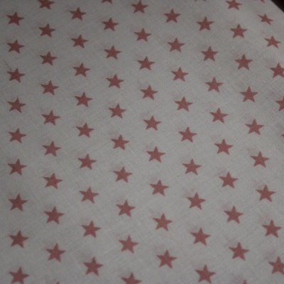 Tecido branco com padrão de estrelas vermelhas