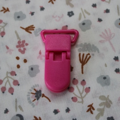 Clipe plástico cor-de-rosa sobre tecido floral