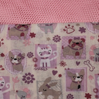 Tecido estampado com desenhos de gatinhos e cachorrinhos em várias cores e padrões, com fundo creme e tecido rosa acima.