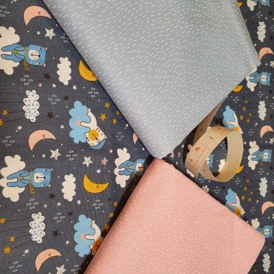 Tecidos coloridos com padrão infantil e liso, em tons azul, rosa e estampado de céu noturno.