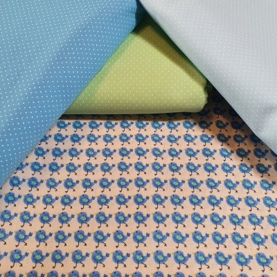 Tecido floral azul e bege com tecidos sólidos azul claro, verde e branco com pequenos pontos.