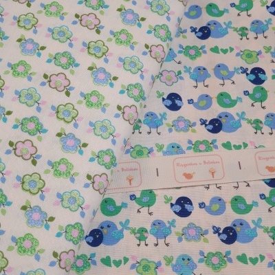 Tecido estampado com flores e pássaros em fundo creme e fita com texto