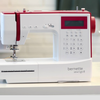 Máquina de costura elétrica branca e vermelha bernette sew & go 8 sobre mesa branca