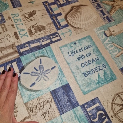 Tecido com padrão náutico azul e bege com conchas e texto