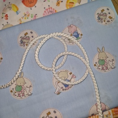 Tecidos infantis com padrões de animais coloridos, cordão branco em cima