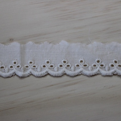 Fita branca bordada em tecido com padrão floral e bordas onduladas